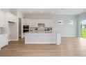 Bright kitchen features a large island, white cabinetry, stainless steel appliances and wood flooring at 5222 Sw 88Th Cir, Ocala, FL 34481