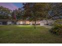 Charming single-story home with a spacious front yard and a traditional American flag at dusk at 18 Pine Circle Dr, Ocala, FL 34472