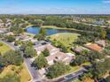 Scenic aerial view showcasing a neighborhood with a golf course, lake, and well-maintained homes with mature trees at 417 Lake Butler Dr, Kissimmee, FL 34759