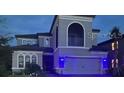 Night view of two-story home with gray exterior, three-car garage, and landscape lighting at 1851 Goblet Cove St, Kissimmee, FL 34746