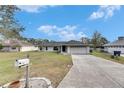 Charming one-story home with a well-manicured lawn and a long driveway under a beautiful sky at 1060 Colony Park Dr, Lakeland, FL 33813