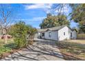 Inviting single-story home with a long driveway, an attached garage, and lush landscaping at 116 Woodlane Ave, Wildwood, FL 34785