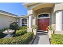 Inviting front entrance with a red double door, lush landscaping, and elegant decorative features at 8867 Pebblebrooke Dr, Lakeland, FL 33810