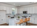 Bright kitchen features white cabinets, quartz countertops, stainless steel appliances, and a tile backsplash at 5295 Sw 87Th Ter, Ocala, FL 34481