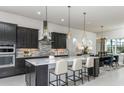 Modern kitchen boasts dark cabinets, a marble island with seating, and designer pendant lighting at 5243 Sw 88Th Cir, Ocala, FL 34481