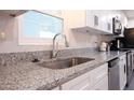 Close-up of a newly renovated kitchen with white cabinets, granite countertops and a stainless steel sink and appliances at 1231 Sidcup Rd, Maitland, FL 32751