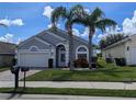 Charming single-story home featuring a two-car garage and mature landscaping, including palm trees at 131 Vine Dr, Davenport, FL 33837
