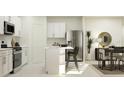 Modern kitchen with stainless steel refrigerator, white cabinetry, and center island with stools at 1799 Teagan Ln, Winter Haven, FL 33884