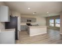 Bright, open kitchen features stainless steel appliances, a center island, and light wood floors at 1905 Harrods Pl, Haines City, FL 33844