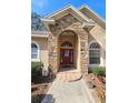 Inviting front entrance with stone facade, arched entryway, and a vibrant red door at 5685 Lake Victoria Dr, Lakeland, FL 33813