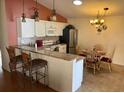 Bright eat-in kitchen featuring white cabinetry, granite countertops, stainless steel appliances and modern light fixtures at 992 Davit Pl, The Villages, FL 32162