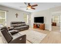 Cozy living room featuring wood-look flooring, neutral walls, a comfortable leather sofa, and a ceiling fan at 3214 Bayou Bay Dr, Lakeland, FL 33811