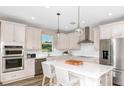 Bright kitchen featuring a large quartz island with seating, stainless steel appliances, and pendant lighting at 1671 Ruby Ln, Lake Alfred, FL 33850