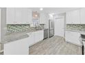 Modern kitchen featuring white cabinetry, stainless steel appliances, and stylish backsplash at 917 E Valencia St, Lakeland, FL 33805