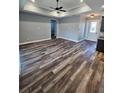 Open-concept living room featuring tray ceilings, ceiling fan and wood-look flooring at 1264 Buckeye Ne Rd, Winter Haven, FL 33881