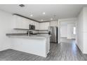 Bright kitchen featuring an island with a breakfast bar, stainless steel appliances and gray wood-look flooring at 409 Ashbury Way, Poinciana, FL 34759