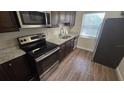 Modern kitchen featuring stainless steel appliances, granite countertops, and dark wood cabinets at 1804 S Mellonville Ave, Sanford, FL 32771