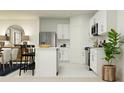 Modern white kitchen featuring stainless steel appliances, bar stool seating, and a dining area at 2027 Town Pasture Dr, Eustis, FL 32726