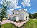 View of the side of a charming two-story townhome showing a brick driveway and well-maintained landscaping at 571 Bay Leaf Dr, Poinciana, FL 34759
