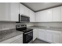 Well-lit kitchen with stainless steel microwave and oven, granite counters, and white cabinetry at 571 Bay Leaf Dr, Poinciana, FL 34759