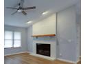 Open living room featuring a painted brick fireplace, hardwood flooring and modern ceiling fan at 290 Ne 51St Ave, Ocala, FL 34470
