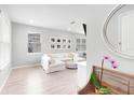 Bright living room with light hardwood floors, a white sectional sofa, and a large circular mirror at 1324 Painted Bunting Ave, Winter Garden, FL 34787