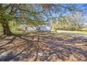 A quaint single-story home with white siding, surrounded by mature trees providing natural shade and privacy at 1140 Saddlewood Blvd, Lakeland, FL 33809