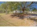 A single-story home with white siding, nestled on a lot with mature trees offering ample shade and greenery at 1140 Saddlewood Blvd, Lakeland, FL 33809