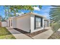 Side view of a well-maintained home with a dark trimmed window, side yard, and concrete walkway at 5152 Belmont Park Way, Mulberry, FL 33860