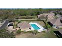 Aerial view of a community pool area with lounge chairs, manicured landscaping, and a nearby clubhouse at 6455 Sedgeford Dr, Lakeland, FL 33811