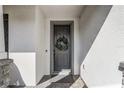 Front entryway featuring a gray front door adorned with a decorative wreath and white stucco walls at 5618 Winterbrook Way, Winter Park, FL 32792