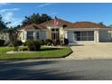 Single-story home with manicured lawn, an American flag, and a spacious two-car garage at 348 Ellenton Run, The Villages, FL 32162