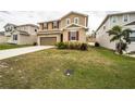 Two-story tan home with red shutters and a lawn at 348 Lake Smart Cir, Winter Haven, FL 33881