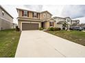 Two-story home with a long driveway leading to a brown garage door and tan and brown siding at 348 Lake Smart Cir, Winter Haven, FL 33881