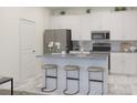 Modern kitchen with stainless steel appliances, white cabinetry and island with bar stool seating at 2569 Cotton Candy Aly, Kissimmee, FL 34744