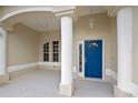 Inviting front porch area showcasing a vibrant blue front door, decorative columns, and charming pendant lights at 113 Grand Reserve Ct, Davenport, FL 33837