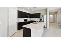 Modern kitchen with black cabinets, stainless appliances, tile floor and island with sink at 1667 Ruby Ln, Lake Alfred, FL 33850