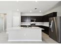 Modern kitchen featuring dark cabinetry, stainless steel appliances, and a central island with sink at 1667 Ruby Ln, Lake Alfred, FL 33850