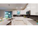 Modern kitchen with white cabinets, stainless steel appliances, and a breakfast bar overlooking backyard at 3217 Armstrong Ave, Clermont, FL 34714