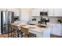 Modern kitchen boasts white cabinets, stainless steel appliances, and a quartz island with seating at 1010 Foreshore Ln, Haines City, FL 33844