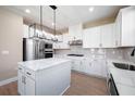 Modern kitchen featuring white cabinets, stainless steel appliances, kitchen island, and stylish light fixtures at 7729 Somersworth Dr, Kissimmee, FL 34747