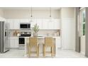Bright kitchen with white cabinets, stainless steel appliances, and an island with seating for two at 2603 Skyline Loop, Kissimmee, FL 34758