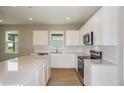 Modern kitchen features white cabinets, stainless steel appliances, quartz countertops and a large center island at 5333 Sw 81St Cir, Ocala, FL 34481