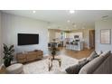 Bright open-concept living room features a modern TV console and stylish decor with seamless access to the kitchen and dining area at 5333 Sw 81St Cir, Ocala, FL 34481