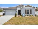 Inviting single-story home with a two-car garage, manicured lawn, and decorative front yard elements at 389 Singing Sands Cir, Lake Wales, FL 33859