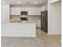 Modern kitchen with white cabinets, stainless steel appliances, and a spacious island at 276 Woodsage Pl, Lake Alfred, FL 33850