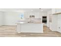 Bright, all-white kitchen featuring an island, modern appliances, white countertops, and light wood floors at 284 Woodsage Pl, Lake Alfred, FL 33850