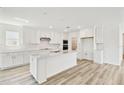 Spacious kitchen with white cabinets, stainless steel appliances, an island, and light wood flooring at 284 Woodsage Pl, Lake Alfred, FL 33850