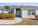 Inviting entrance with manicured flowerbeds, white door, and side windows for natural light at 524 Buckshot Ln, Lakeland, FL 33809