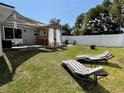 Spacious backyard with lawn featuring striped lounge chairs, covered pergola, and privacy fence at 858 Lafayette Ln, Lakeland, FL 33805